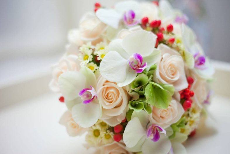 Svatební kytice se světle oranžovými růžemi a bílými orchidejemi