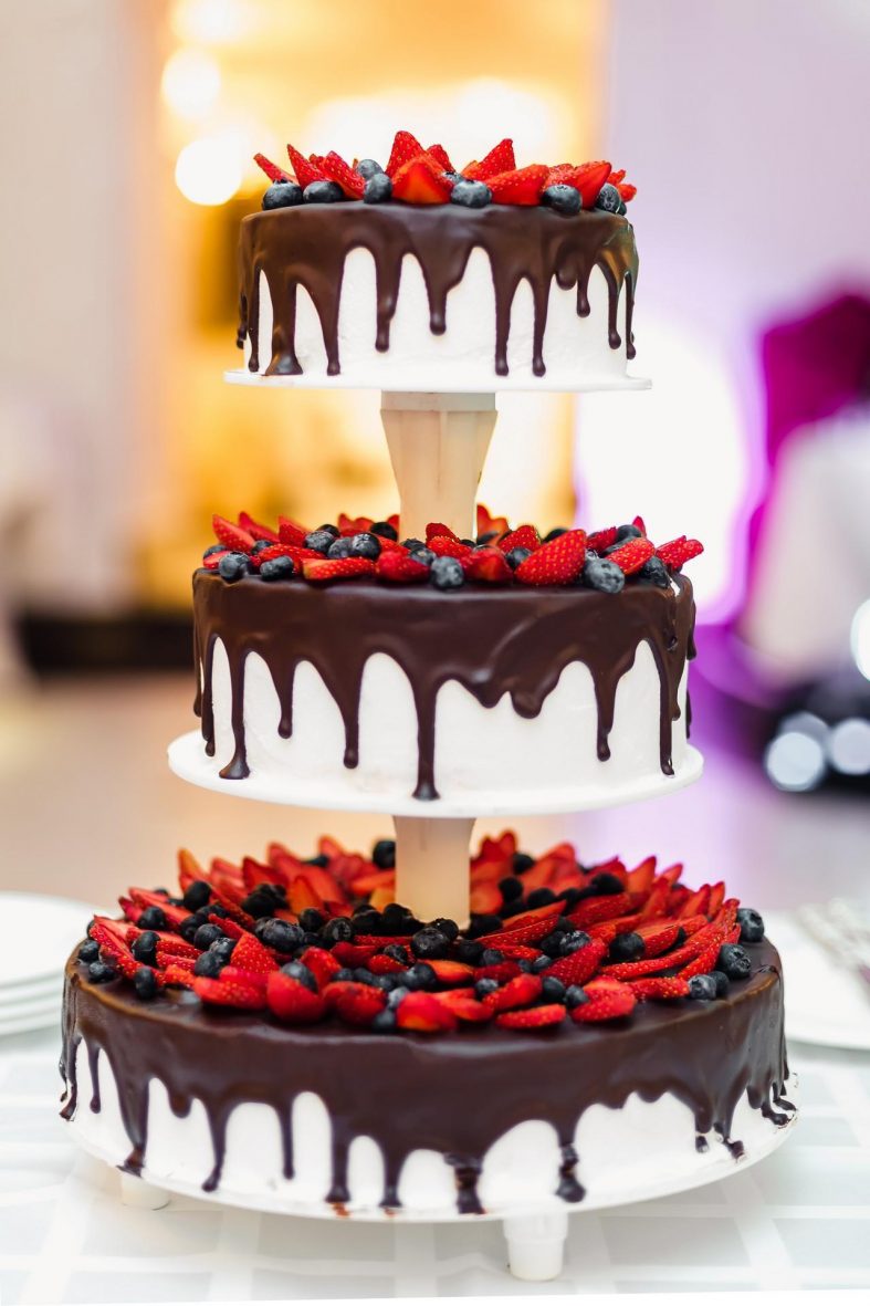 Třípatrový svatební dort politý čokoládou a s lesními plody